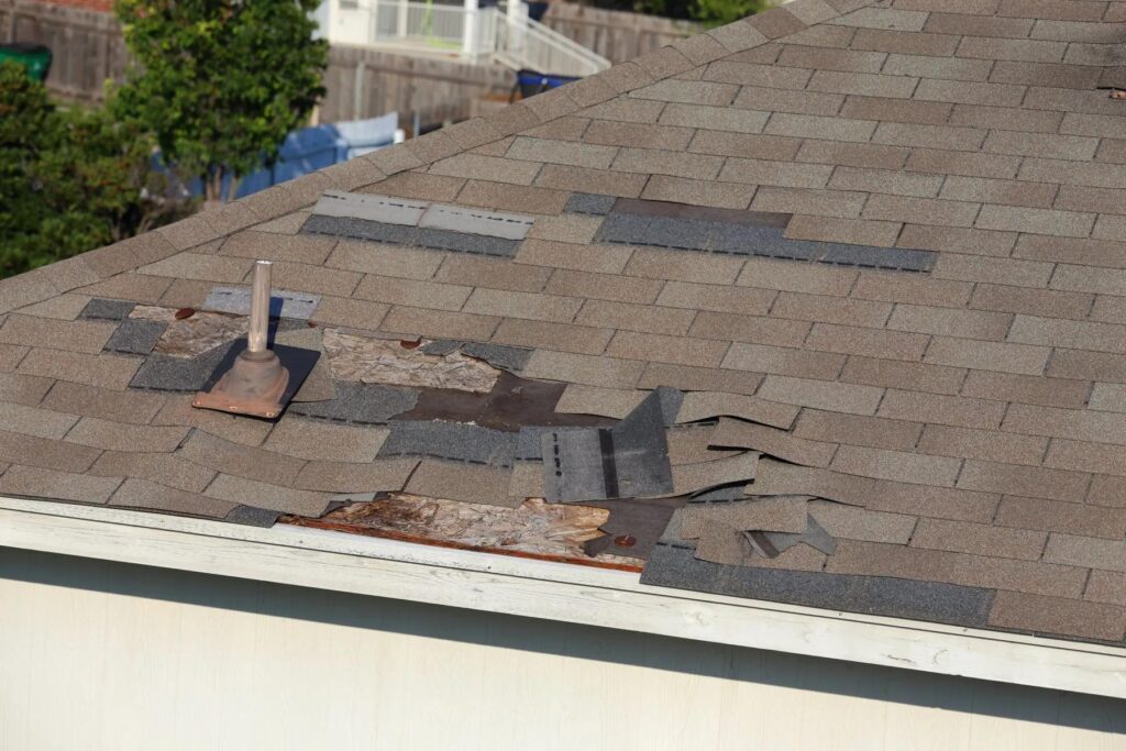 Asphalt shingle roof with wind-damaged and missing shingles